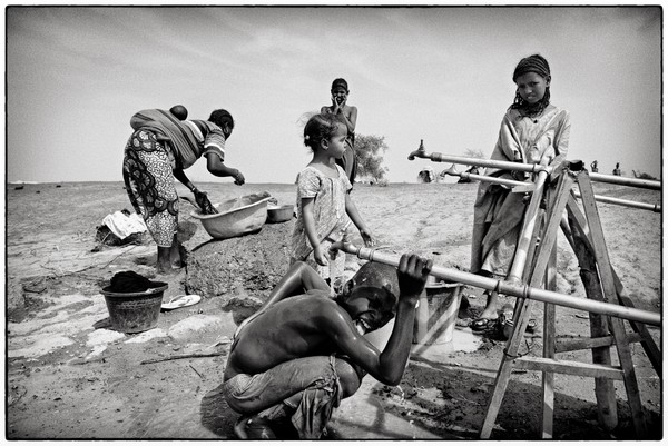Un des points d'eau du camp de Mentao Sud. L'eau est fournie par la Croix-Rouge sous forme de ??? (j'ai oublié le nom des énormes sacs d'eau) acheminés par camions sur zone. Il a fallu instaurer des heures de distribution dont sont chargés les volontaires croix-rouge afin que ces réserves ne soient pas vidées trop rapidement.